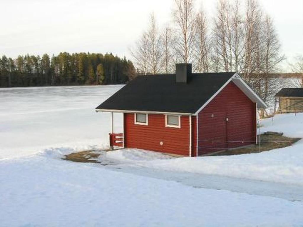 a small red house in the snow with trees in the background at Holiday Home Kallela by Interhome in Jokijärvi