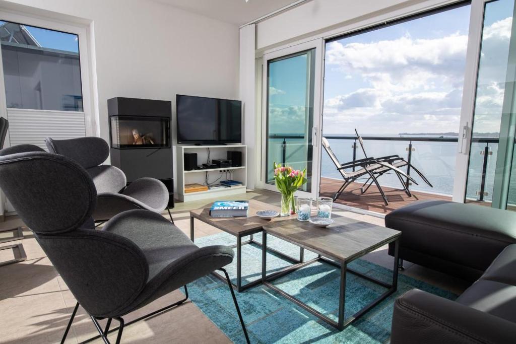 a living room with chairs and a tv and a table at Dock 76 Promenade in Olpenitz