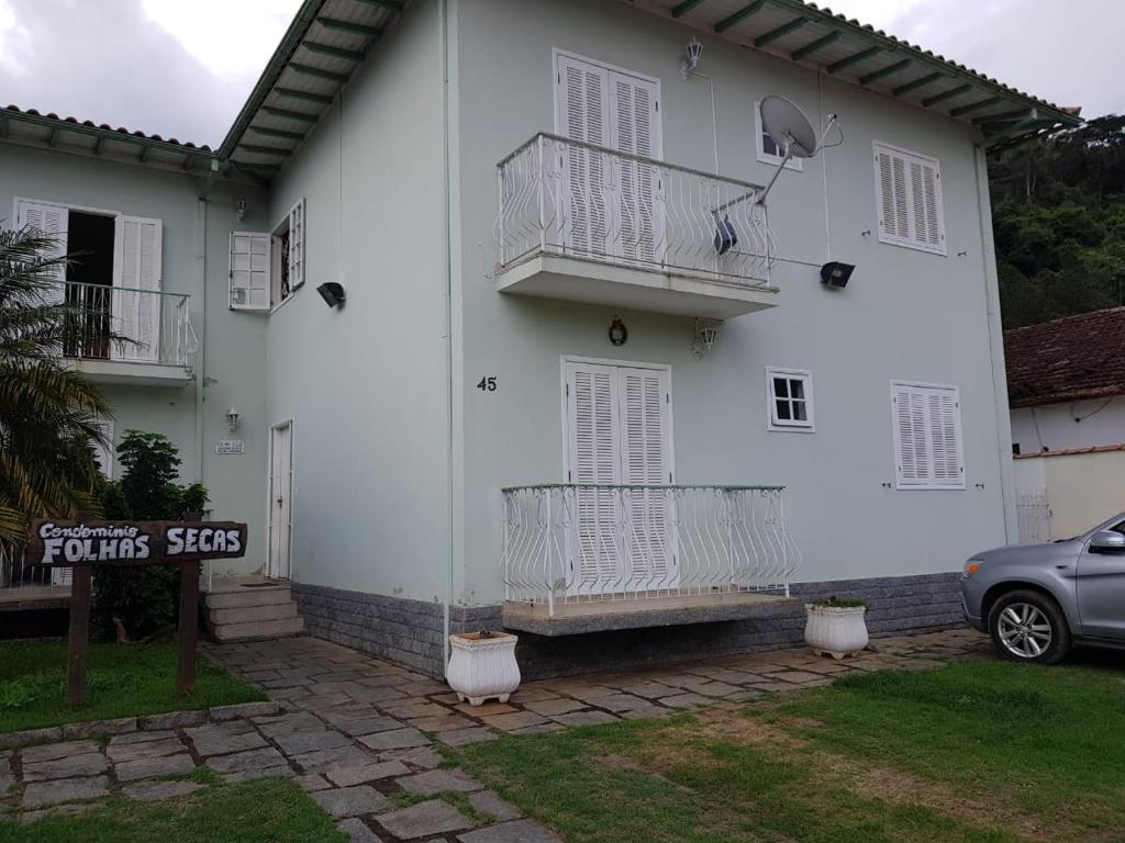 Casa blanca con balcón y coche en Condominio Folhas Secas, en Conservatória
