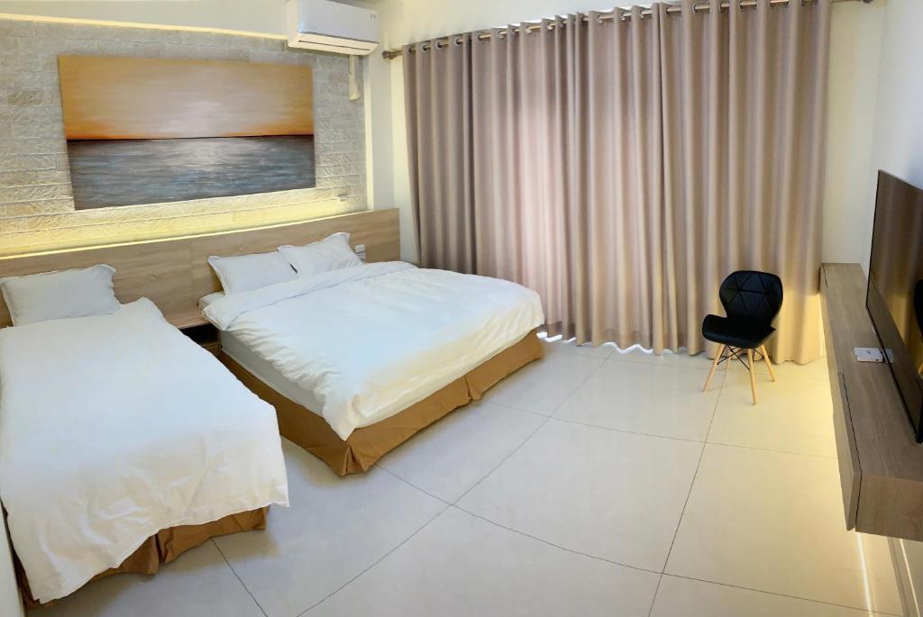 a hotel room with two beds and a television at 里舍民宿 in Jincheng