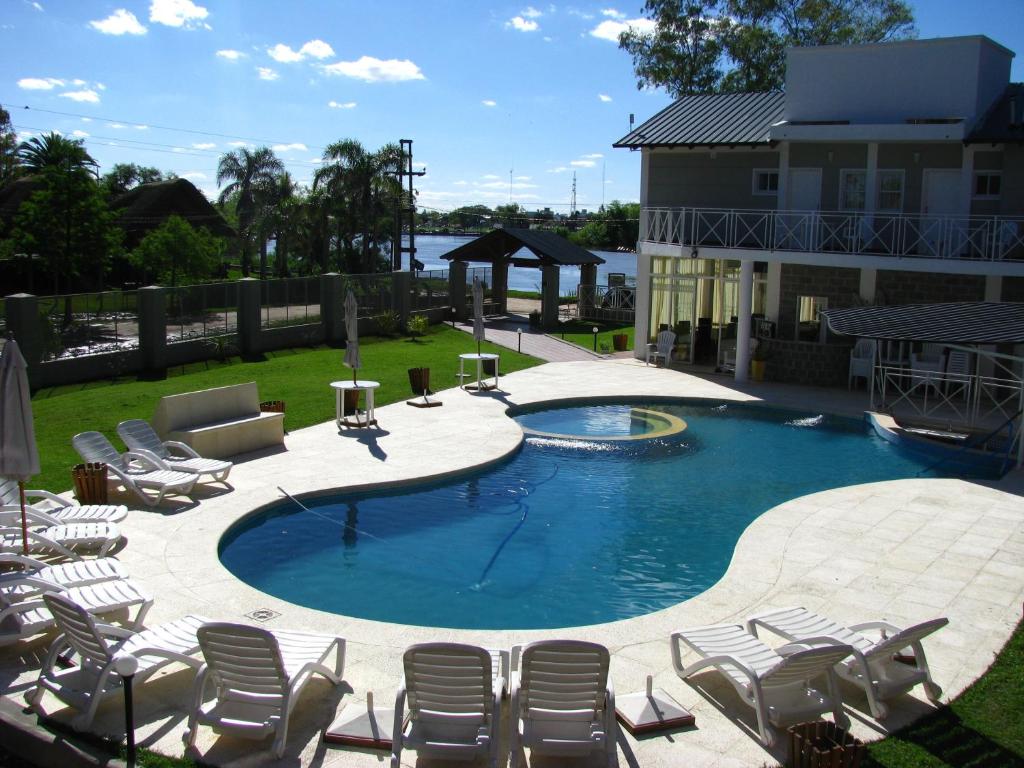 a large swimming pool with chairs and a patio at Placeres de la Costa in Gualeguaychú