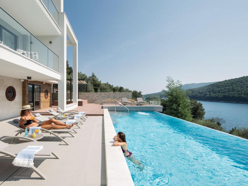 een huis met een zwembad waar mensen op stoelen zitten bij Villa Vlastelini II by Interhome in (( Hrvatini ))