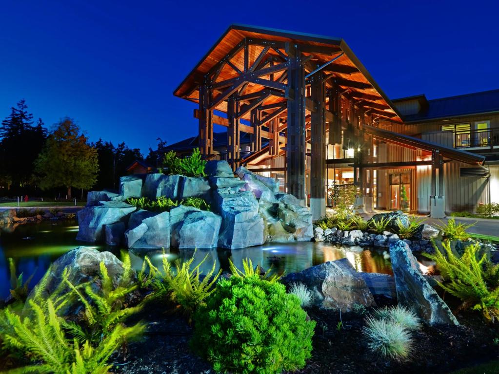 a house with a pond in front of a building at Sunrise Ridge Waterfront Resort in Parksville