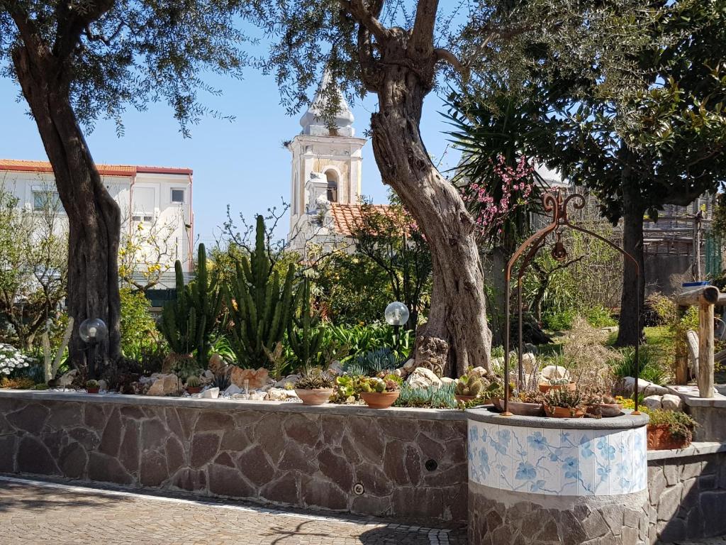 un jardin avec des plantes en pot et une tour en arrière-plan dans l'établissement Villa Kalimera, à Sorrente