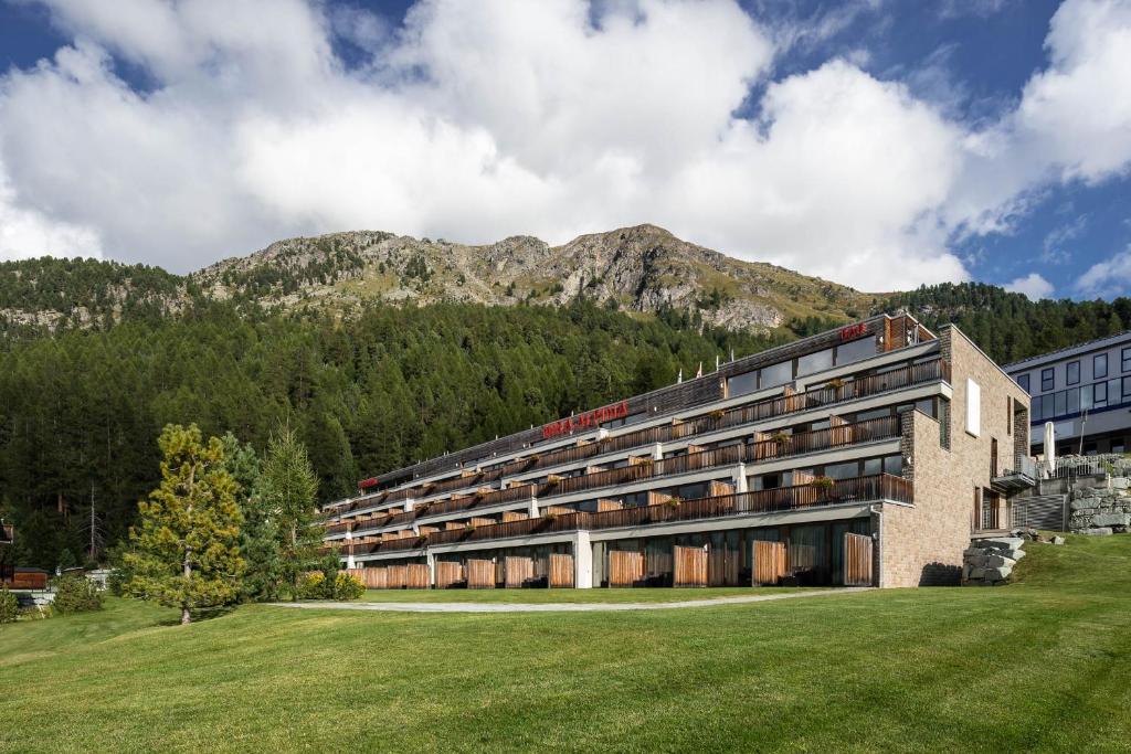 un grand bâtiment avec une montagne en arrière-plan dans l'établissement Nira Alpina, à Silvaplana