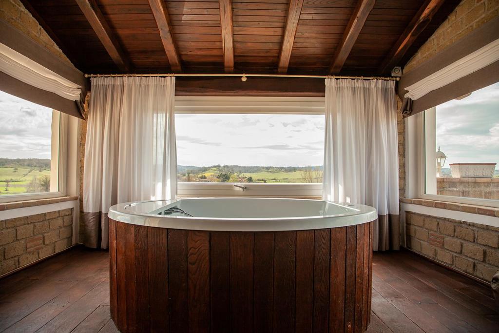 bañera en una habitación con ventana grande en Villa & Spasuitebo Roma, en Mazzano Romano