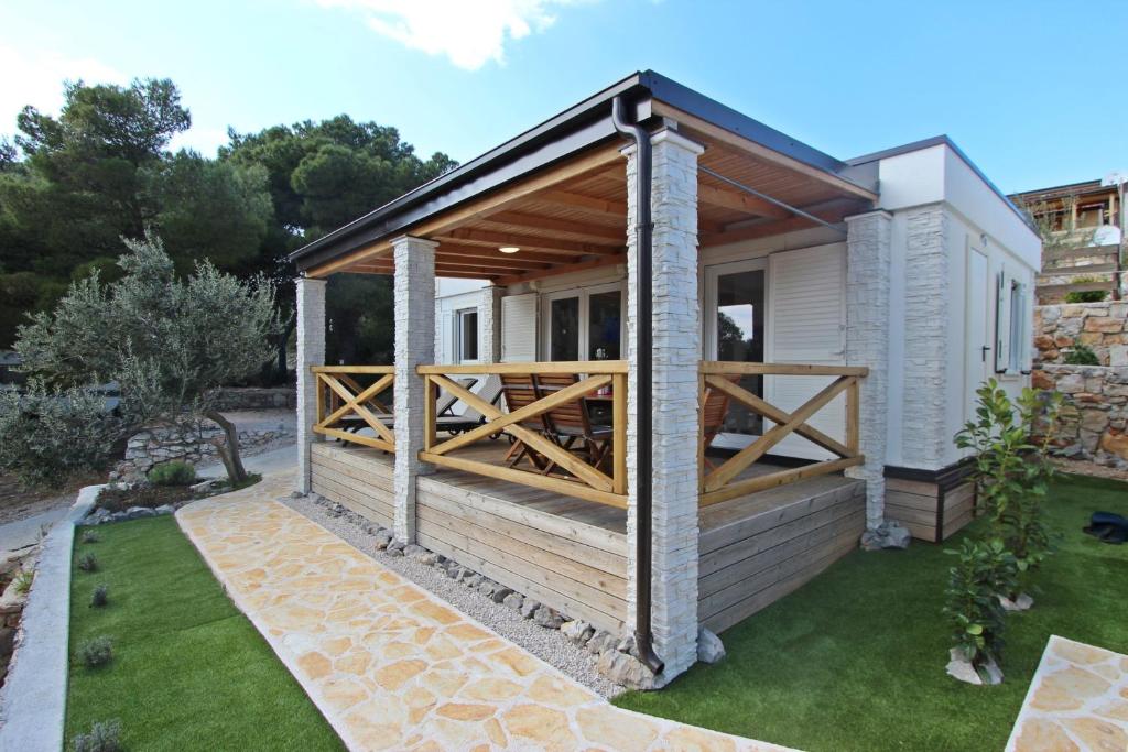 a house with a wooden deck on a yard at Vegros Mobile Homes Slanica in Murter