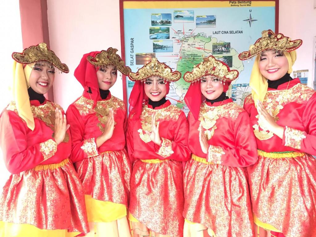 um grupo de raparigas vestidas de vermelho e dourado em Belitung Backpacker em Tanjung Pandan