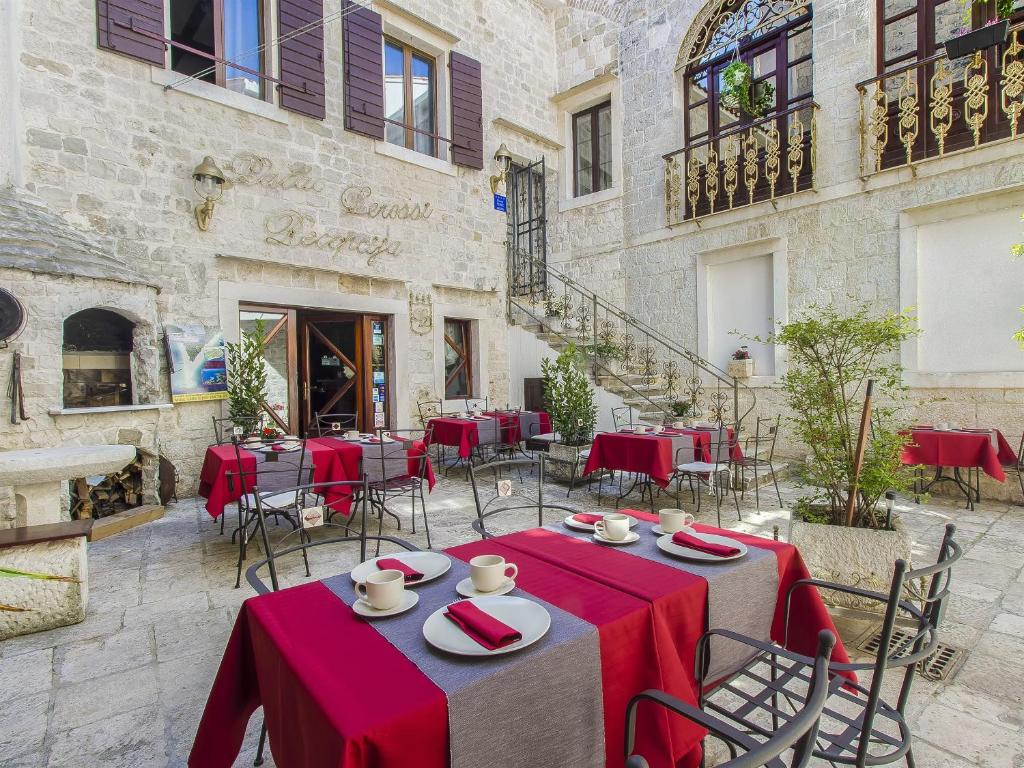 ein Restaurant mit roten Tischen und Stühlen vor einem Gebäude in der Unterkunft Palace Derossi in Trogir