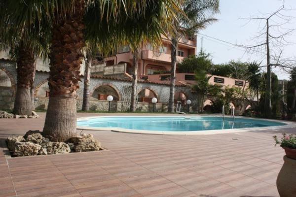 a swimming pool with a palm tree and a building at B&B Angolo Di Paradiso in Pellaro