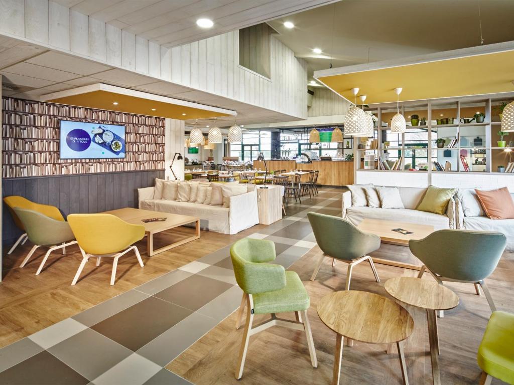 - un hall avec des tables, des chaises et un canapé dans l'établissement Campanile Poitiers - Site du Futuroscope, à Chasseneuil-du-Poitou