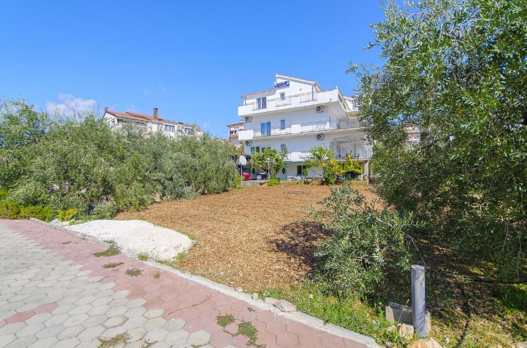 ein großes weißes Gebäude mit einem Hof davor in der Unterkunft Apartments Ljuba - nice garden in Trogir