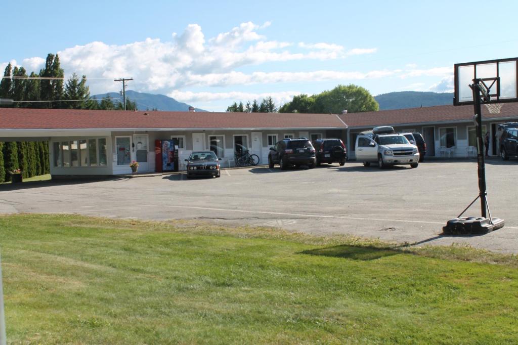 a building with cars parked in a parking lot at Paradise Motel in Sicamous