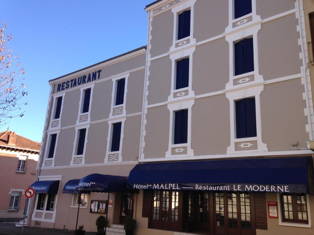 a large white building on the corner of a street at Hôtel Malpel in Decazeville