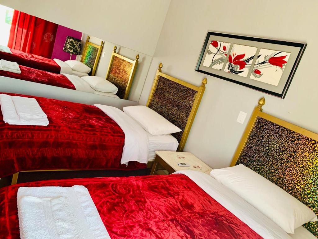 een kamer met drie bedden met rode en witte lakens bij Prince Hotel Fier in Fier