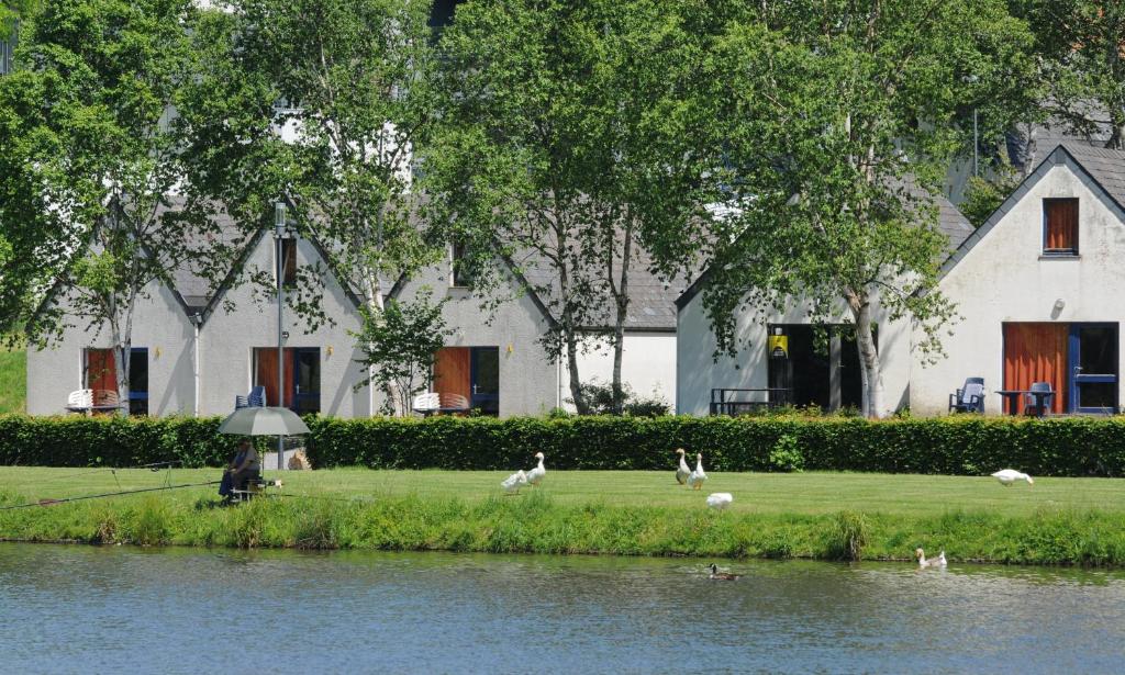 une personne avec un parapluie se promenant à côté d'un lac dans l'établissement Maison du Lac Vielsalm, à Vielsalm