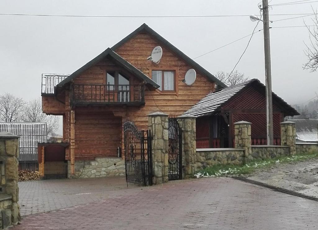 une maison en bois avec une clôture devant elle dans l'établissement На Беріжку, à Mykulychyn