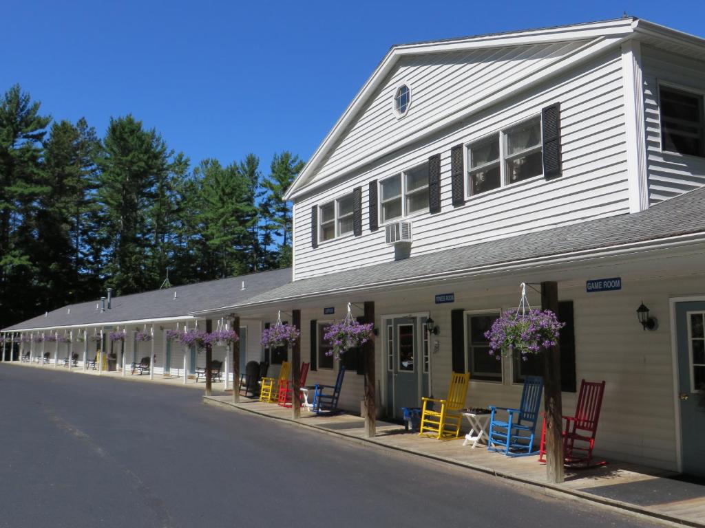 a white building with colorful chairs in front of it at Bayside Inn & Marina in Cooperstown