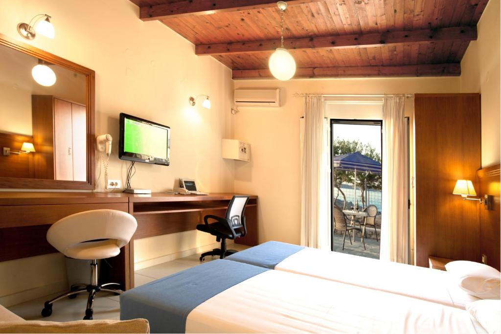 a bedroom with a bed and a desk with a computer at Giorgi's Blue Apartments in Kalathas