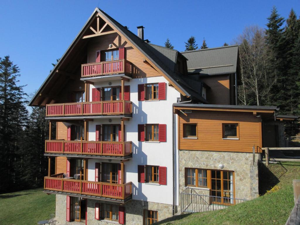 ein Apartmenthaus mit roten Balkonen auf einem Hügel in der Unterkunft Luxury Apartments Bolf in Hočko Pohorje