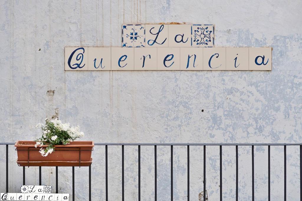 een bord op een muur met een plant op een hek bij La Querencia in Palermo