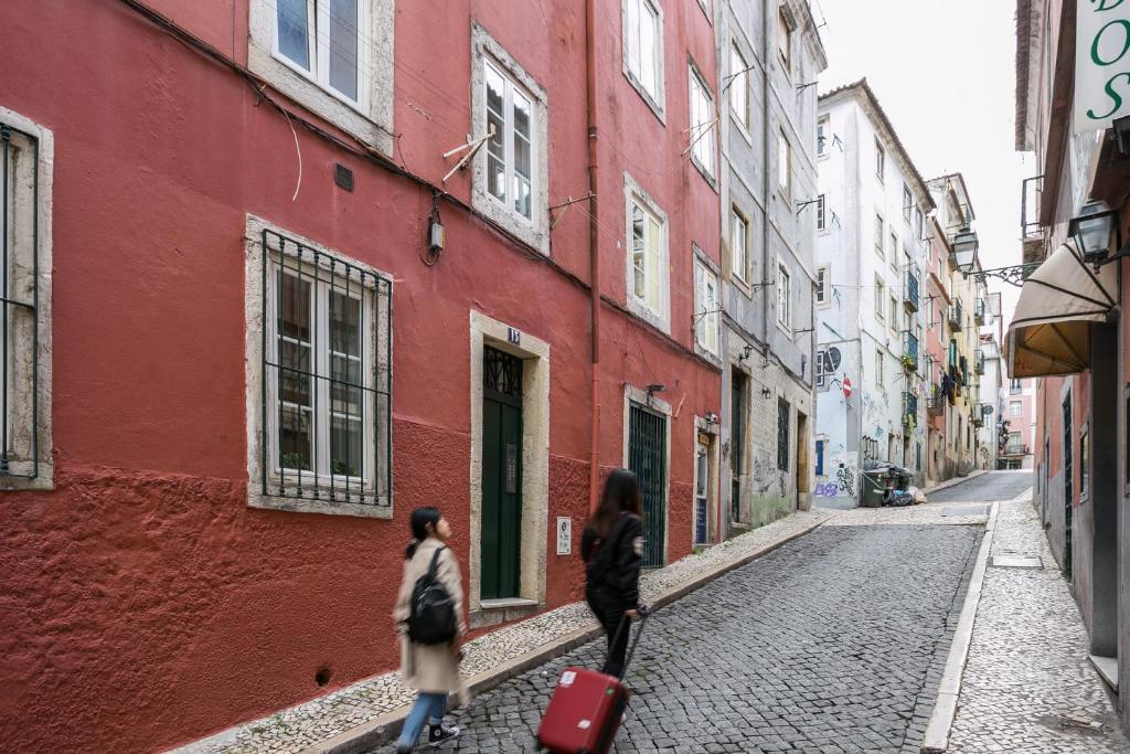 two people walking down a cobblestone street at Cozy Studio in Central Bairro Alto in Lisbon