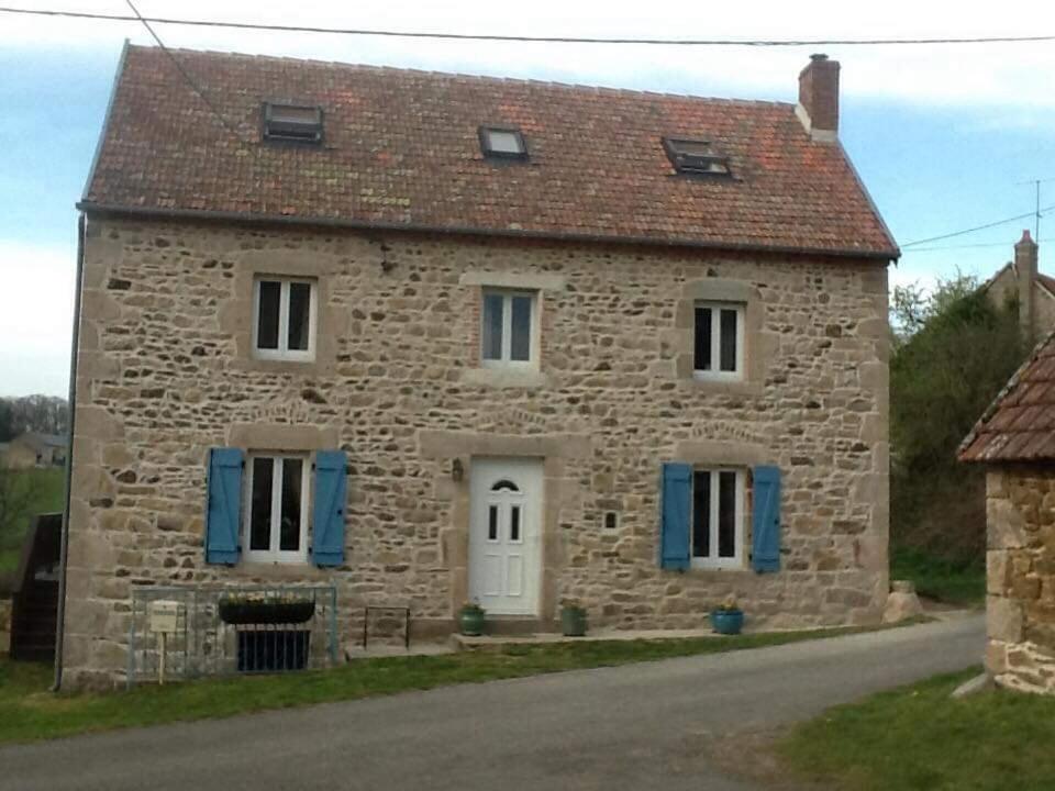 una vieja casa de piedra con persianas azules. en Chez Sivade Gîte, en La Crouzille