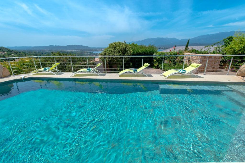 a swimming pool with four chairs in front of a fence at Private Hôtel - Adult Only in Porto-Vecchio