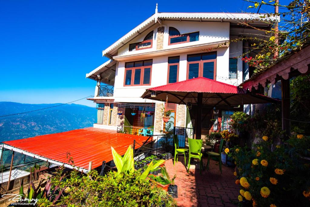 a house with a red roof and an umbrella at Dreamhome Stay in Kurseong