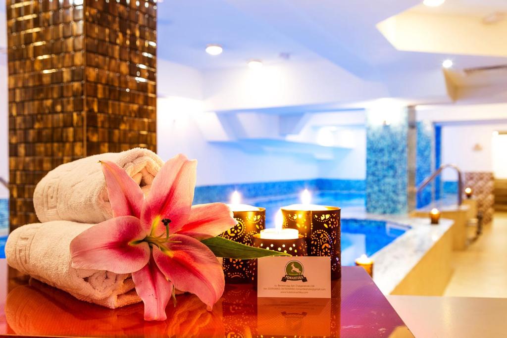 a pink flower sitting on top of a table with candles at Family Hotel Romantika in Velingrad