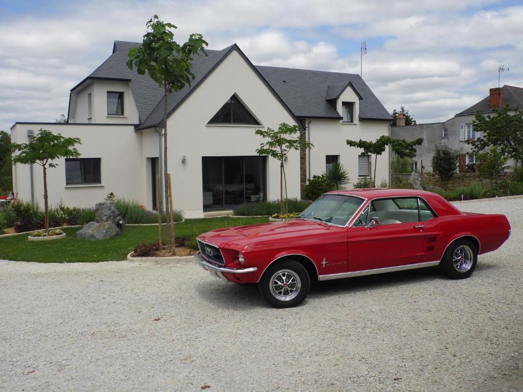 a red car parked in front of a house at AU PARFUM DES LAVANDES in Précigné