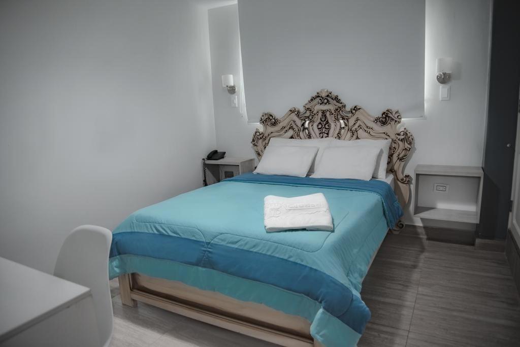 1 dormitorio con 1 cama con manta azul y almohadas blancas en Hotel Ciudad Latin Palace, en Guayaquil