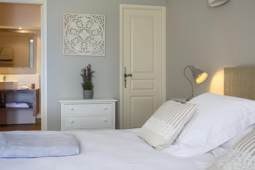 a bedroom with a white bed with a lamp and a door at Les Terrasses du Luberon in Bonnieux