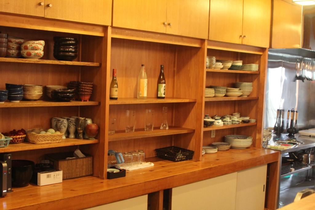 a kitchen with wooden shelves with bottles and dishes at Shaq Bighouse in Kanazawa