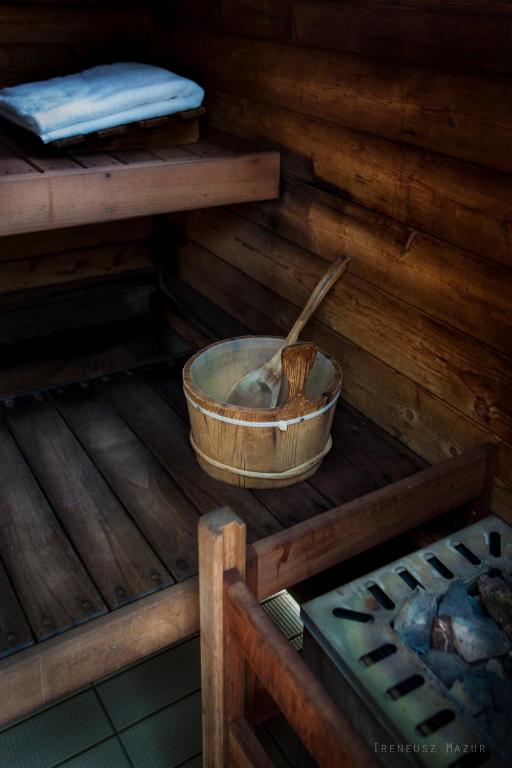 Wooden sauna interior with towel on bench and water bucket with ladles, quiet atmosphere.