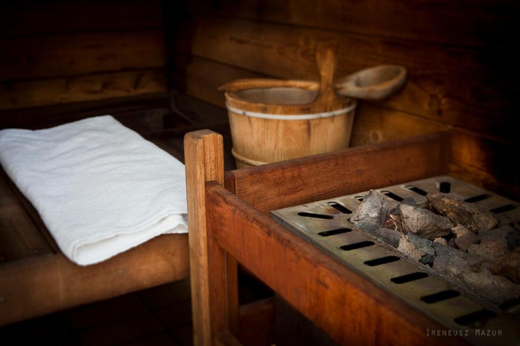 Sauna interior with wooden bench, folded towel, water bucket and hot stones, warm ambiance