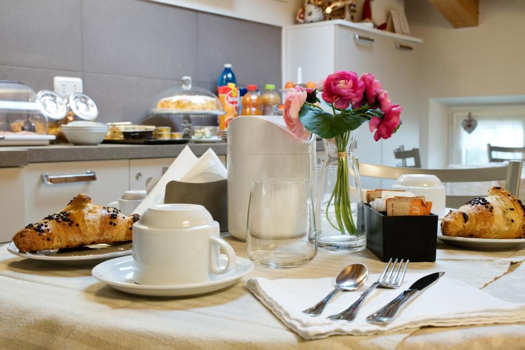 una mesa con platos de comida y un jarrón de flores en B&B La Casa di Rosa, en Vago