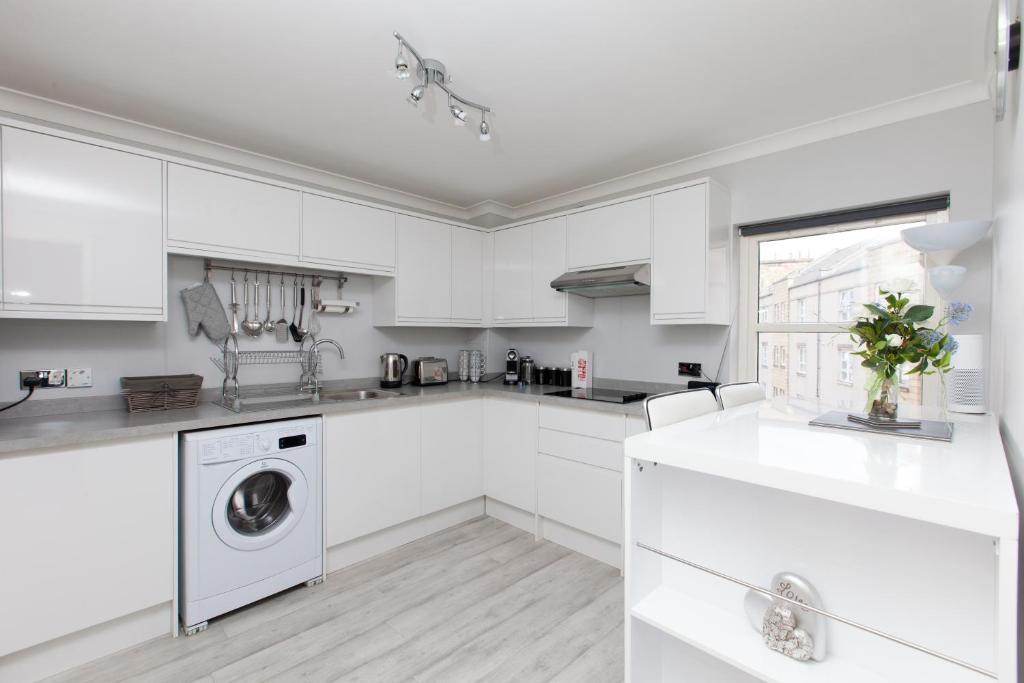 a white kitchen with a washer and dryer at amazing apartments - Annandale St near The Playhouse - Free Parking in Edinburgh