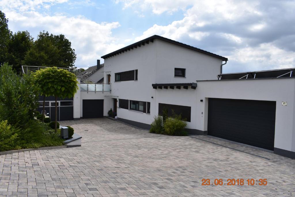 ein weißes Haus mit zwei Garagentüren und einer Einfahrt in der Unterkunft Ferienwohnungen an der Liebesleite Anita Pratsch in Riedenburg