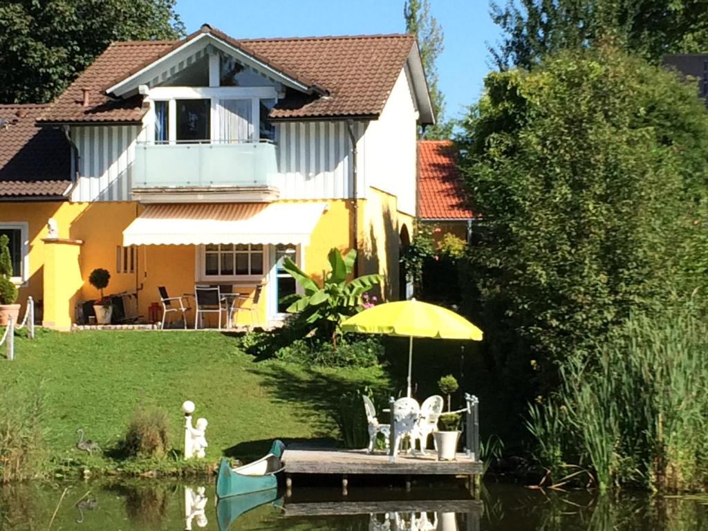 a house with an umbrella and a boat in the water at Traumferienhaus Pfänderblick mit 4 Sternen in Hergensweiler