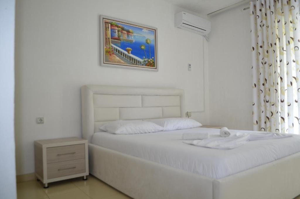a white bedroom with a bed and a picture on the wall at Villa Viktor in Sarandë
