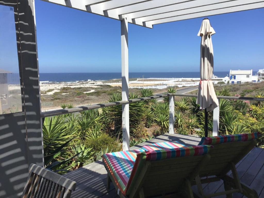 a porch with a chair and an umbrella and the beach at Chez James in Yzerfontein