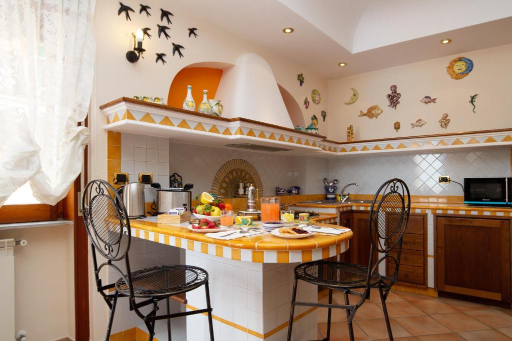 uma cozinha com duas cadeiras e um balcão com pássaros na parede em Domus Amalfi Coast em Maiori