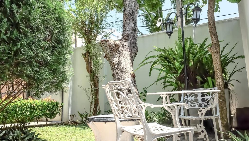 um par de cadeiras brancas sentadas ao lado de uma árvore em Vivid Colombo em Colombo