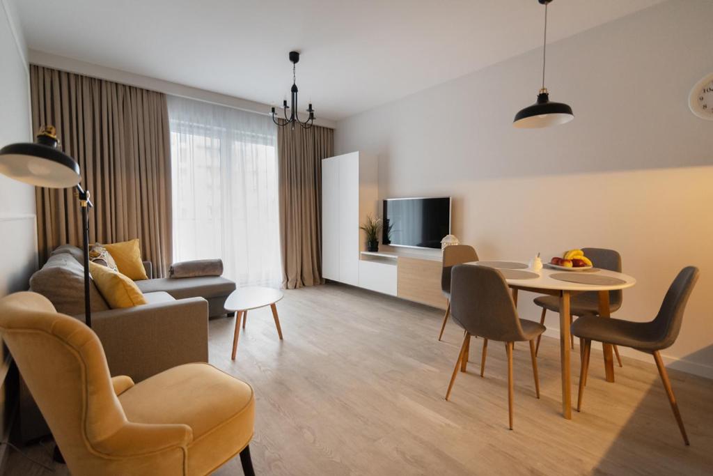 sala de estar con sofá, mesa y sillas en Apartament Tuwima Park, en Olsztyn