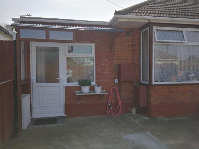 een rood bakstenen huis met een witte deur en een raam bij Rest room near to Heathrow Airport in Ashford