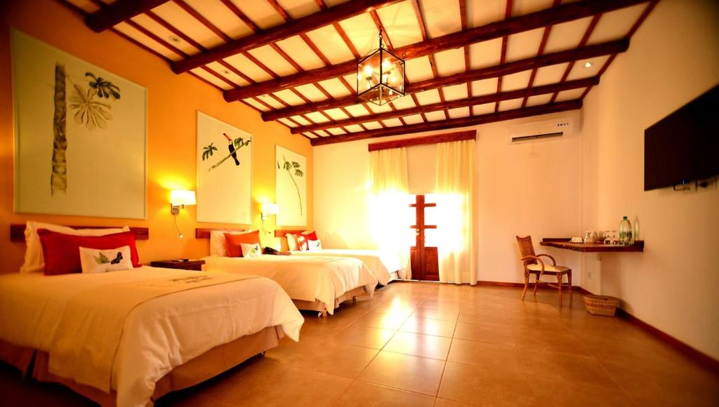 a bedroom with two beds and a cross on the wall at El Pueblito Iguazú in Puerto Iguazú