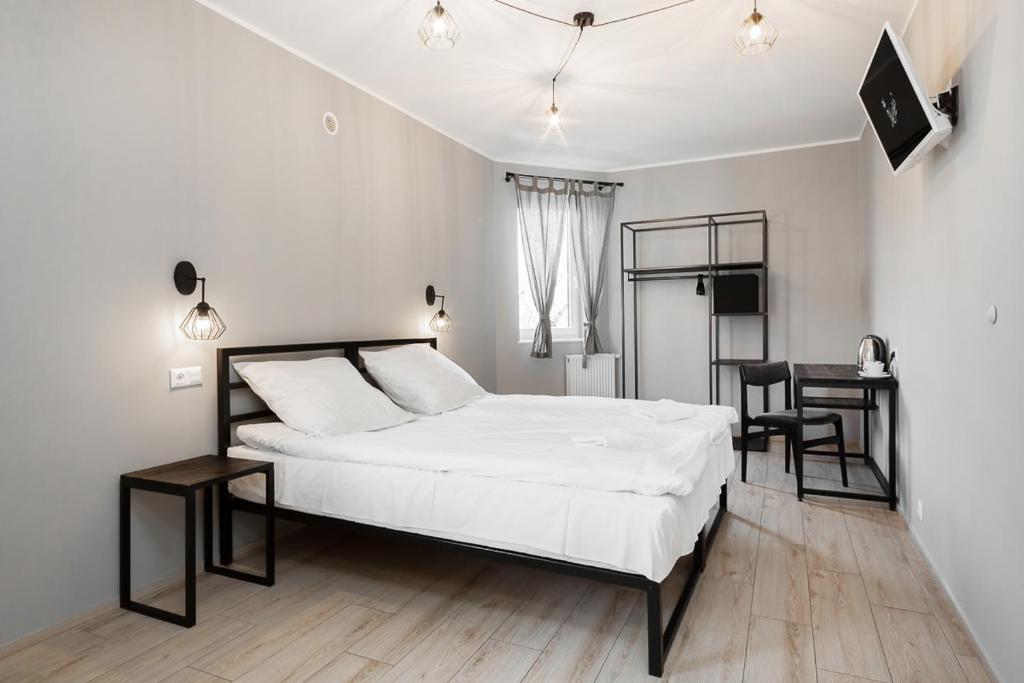 sypialnia z białym łóżkiem, stołem i krzesłami w obiekcie Lemon w Piotrkowie Trybunalskim
