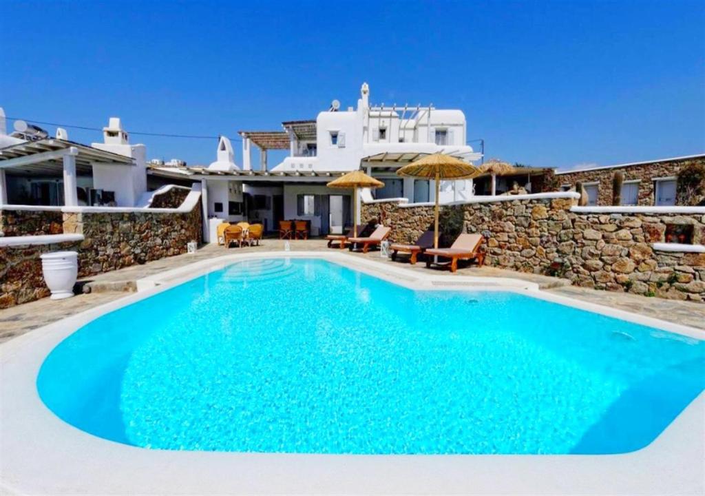 a swimming pool in front of a house at Happy Villas Mykonos in Kalafatis