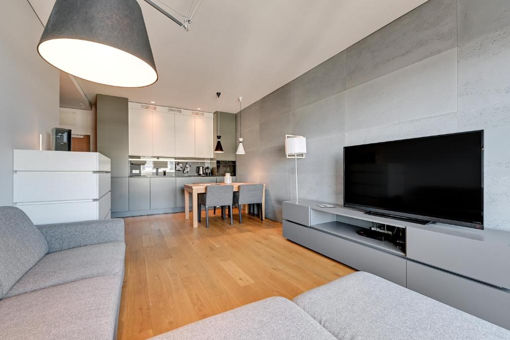 Una sala de estar con un televisor grande y una mesa. en Wave Apartments - Cztery Oceany, en Gdansk